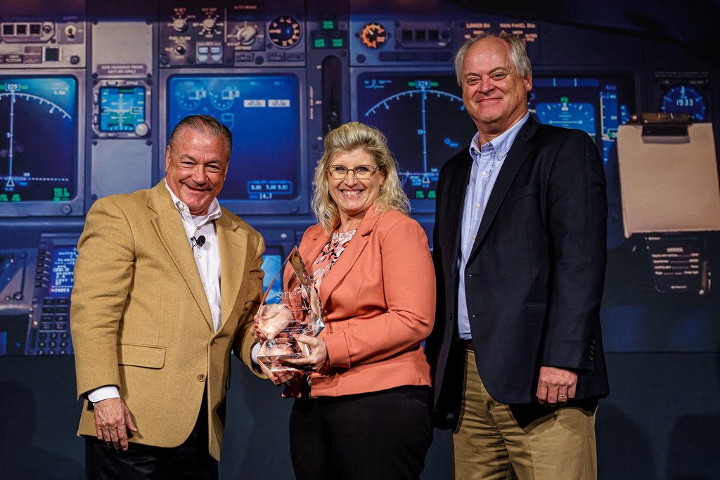 Spirit AeroSystems' Cindy Hoover, accepts the 2021 SME Award for Excellence in Composites Manufacturing (Large Company) Award from Michael Packer, President of the Board of Directors for SME. At right is Blaise Bergmann, Spirit AeroSystems Ultracompetitive Composite Distinctive Capability Leader and Technical Fellow